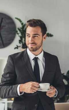 happy-young-businessman-with-cup-of-coffee-at-offi-2021-08-31-22-17-08-utc-Custom-e1643050912197.jpg